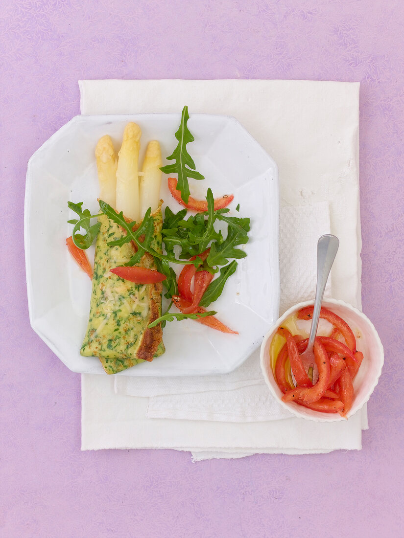 Asparagus parcels with tomato vinaigrette and arugula on plate