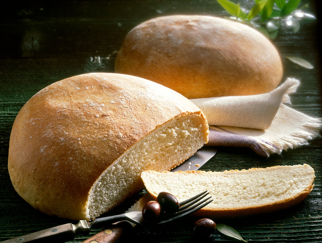 Close-up of Greek country breads with olives on fork