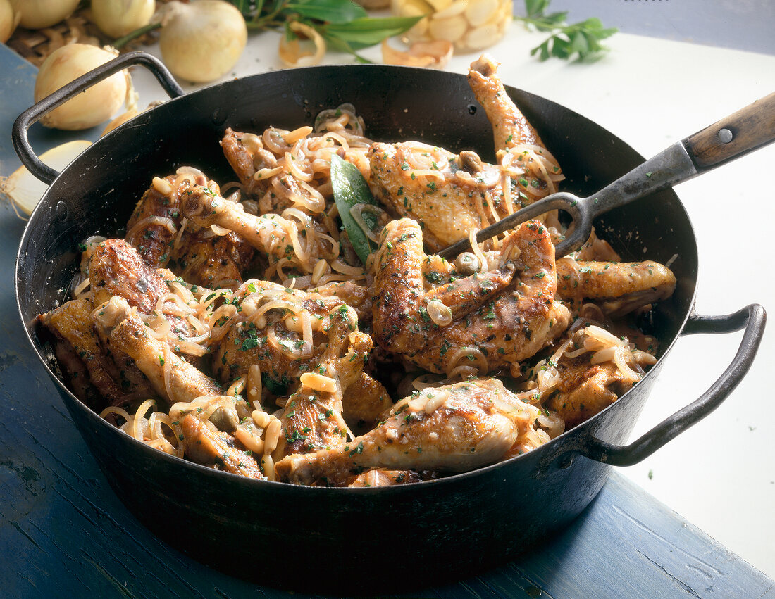 Close-up of braised guinea fowl with onions and pine nuts in casserole