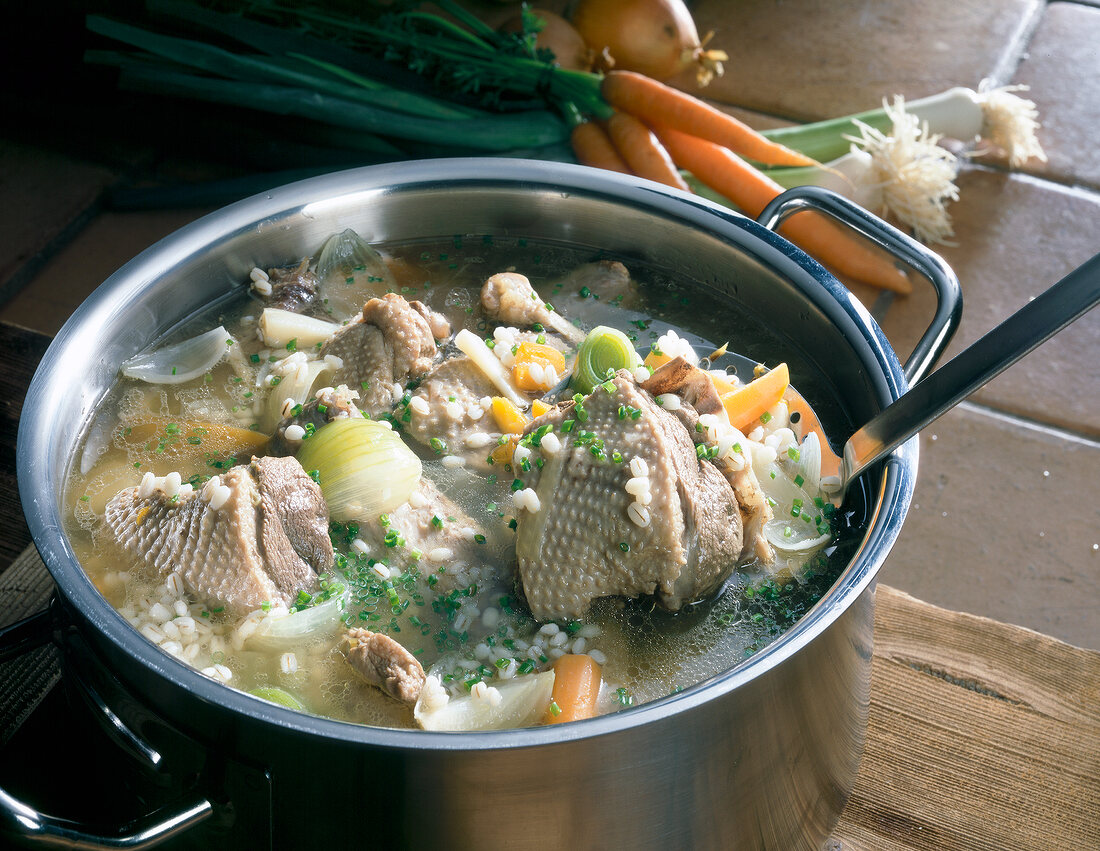 Close-up of chicken pieces with chilli and coriander in pot