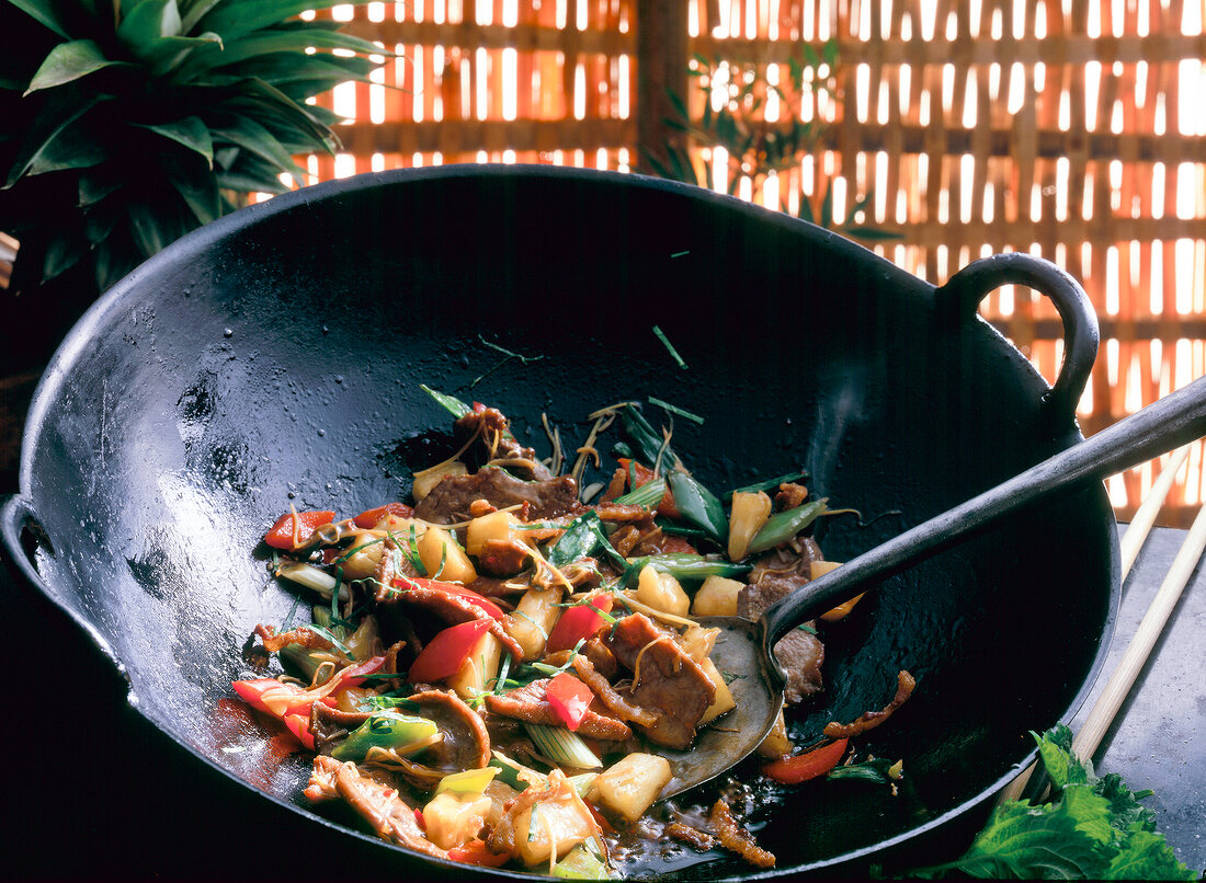 Duck with ginger, pineapple, bell peppers being fried in wok