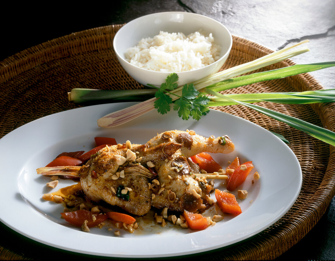 Close-up of chicken with lemongrass, chopped nuts and rice on plate