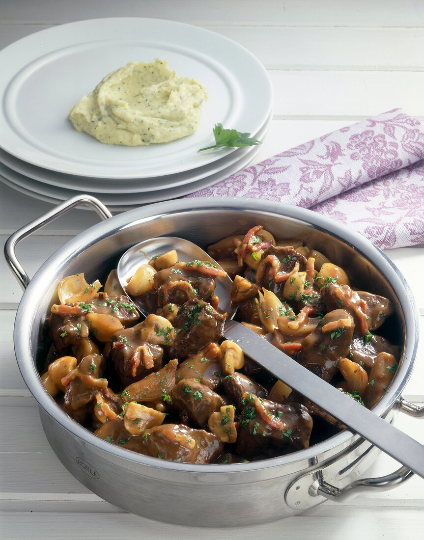 Ostrich stew with mushrooms and spoon in pan