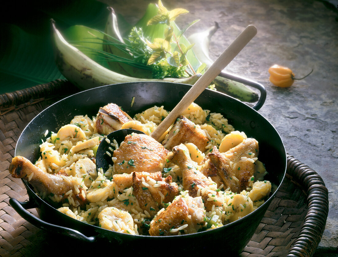 Crispy chicken with rice and bananas in pan with spoon