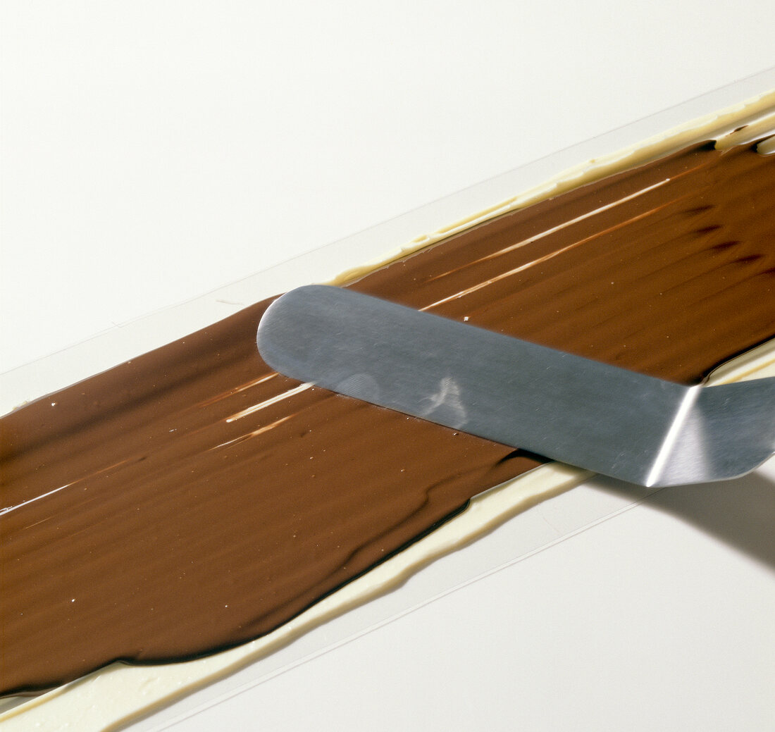 Close-up of dark chocolate being smoothened on white chocolate, step 3