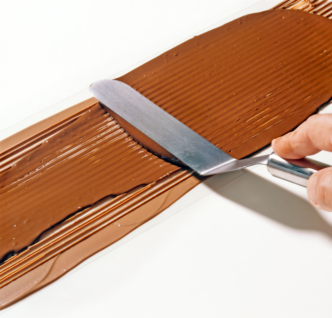 Close-up of dark chocolate being smoothened with pallet, step 4