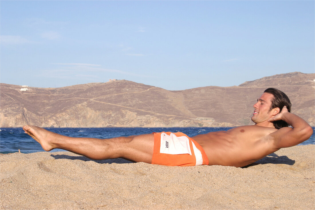 A man doing abdominal exercises on the beach