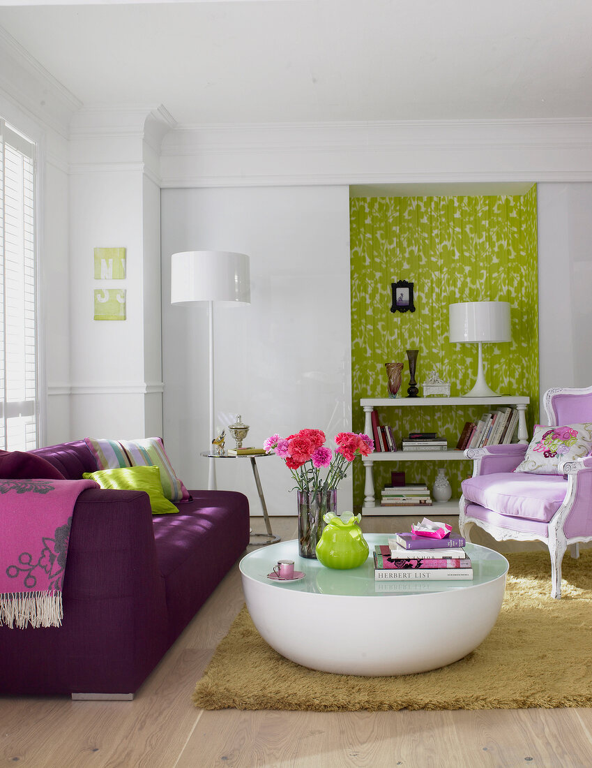 Living room with purple sofa, upholstered chair and white table against green niche