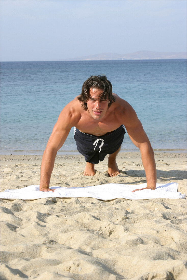 A man doing pushups on the beach