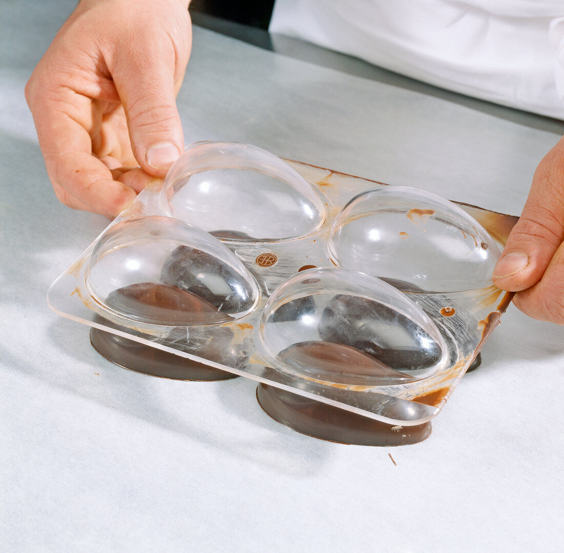 Chocolate eggs being taken out from moulds, step 5