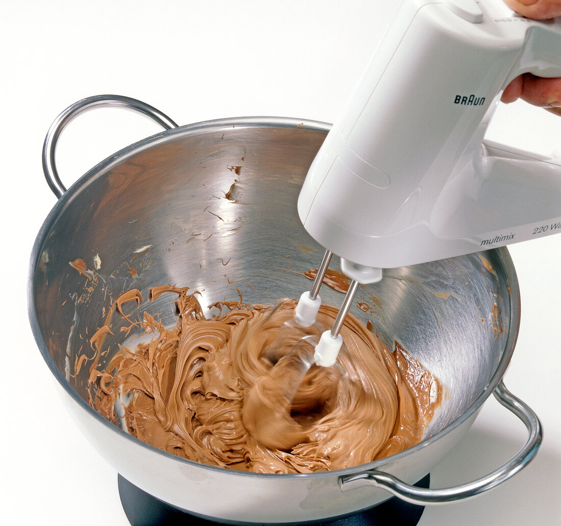 Close-up of butter chocolate mixture being beaten in pan with beater, step 2