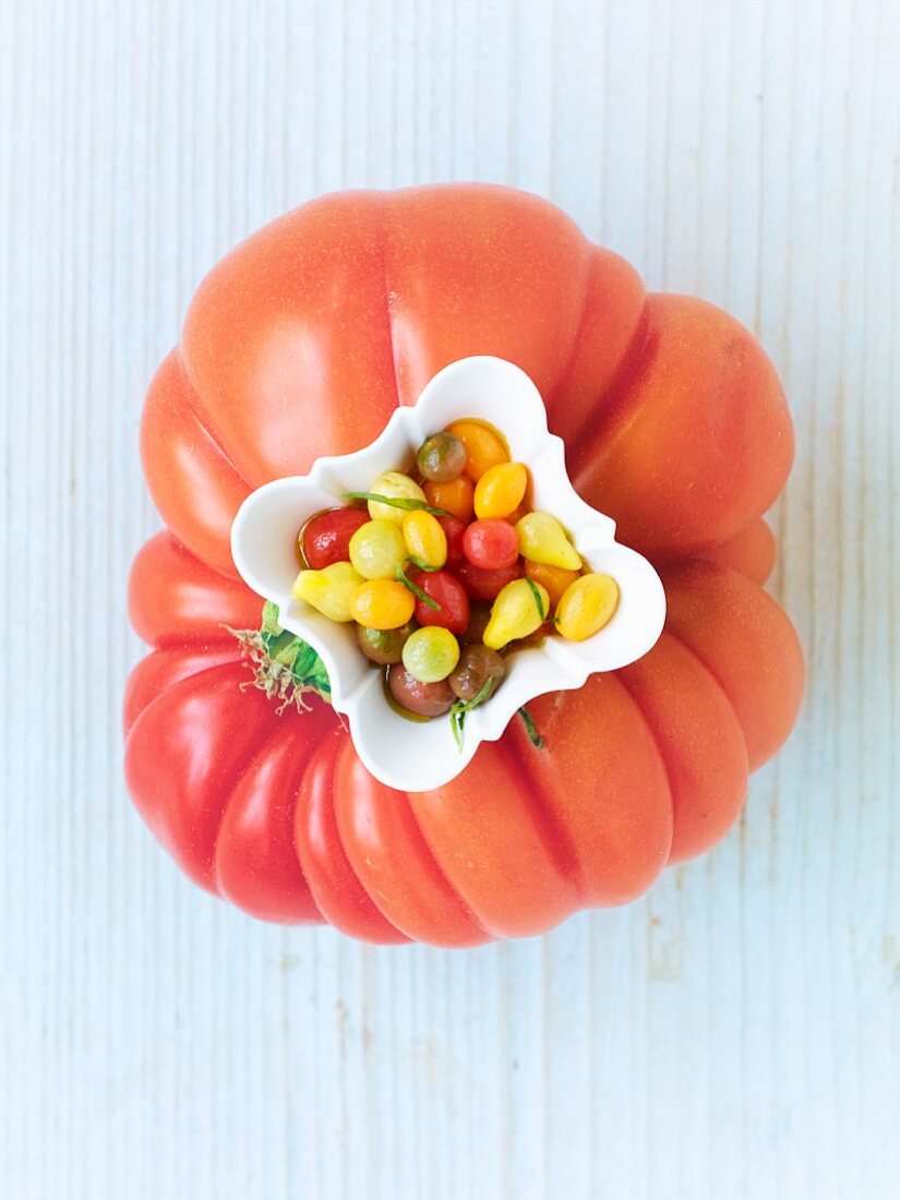 Kleine marinierte Tomaten in Schälchen auf großer Tomate