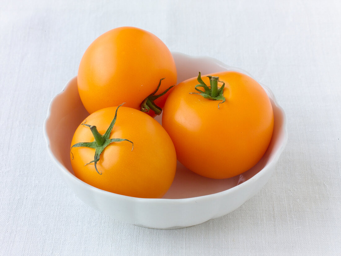 Three yellow tomatoes in bowl