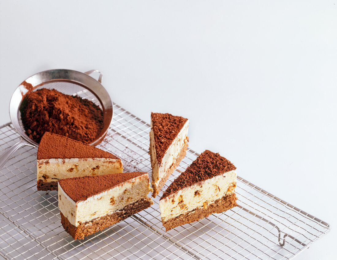 Pieces of hazelnut chocolate cake on grid with cocoa powder