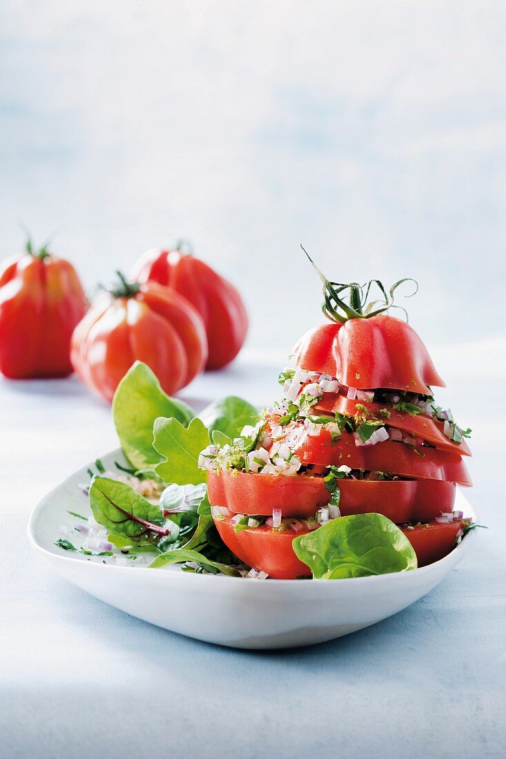 A stack of tomatoes with a coriander and parsley vinaigrette