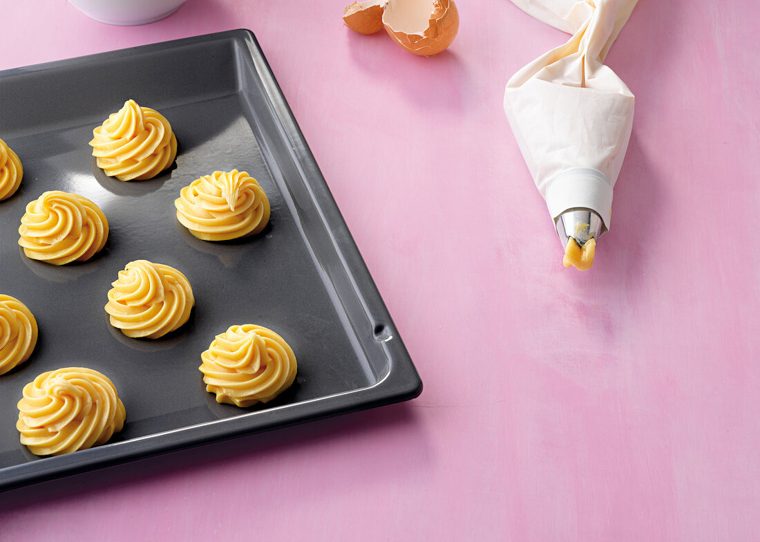 Piping bag and pastries on baking tray