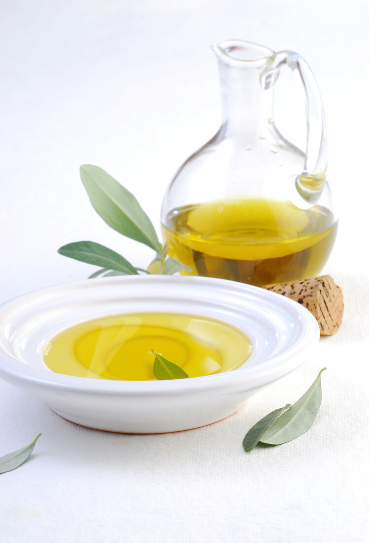 Olive oil in carafe and bowl on white background