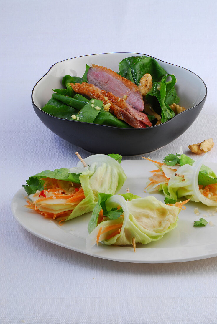 Salad with duck in bowl and papaya salad on plate