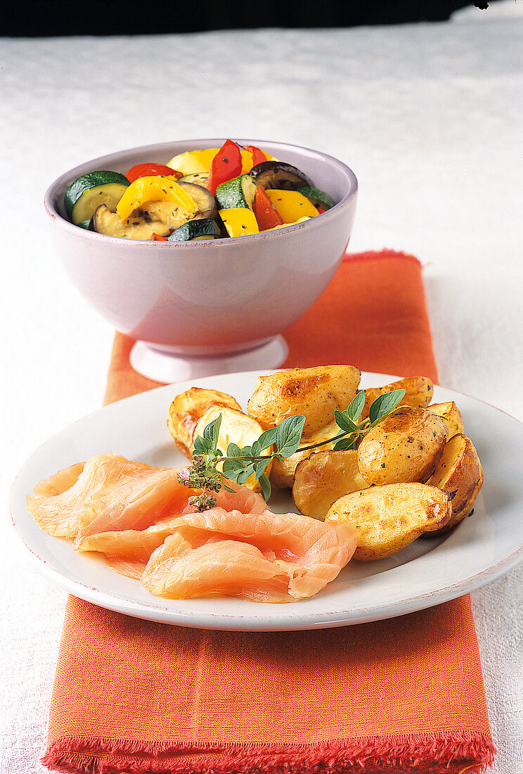Bowl of vegetables and plate of baked potatoes with smoked salmon