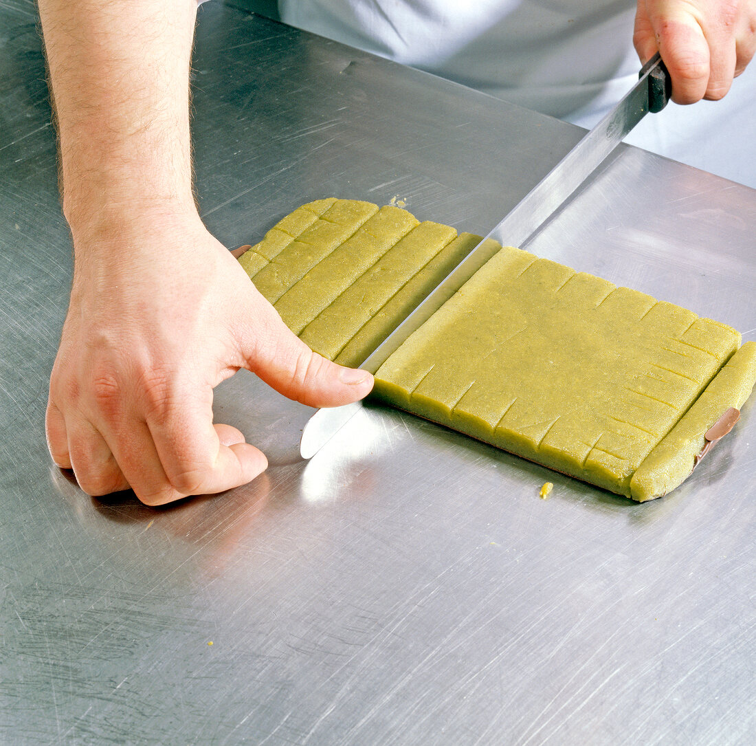 Chef cutting marzipan-pistachio rolled dough, step 5