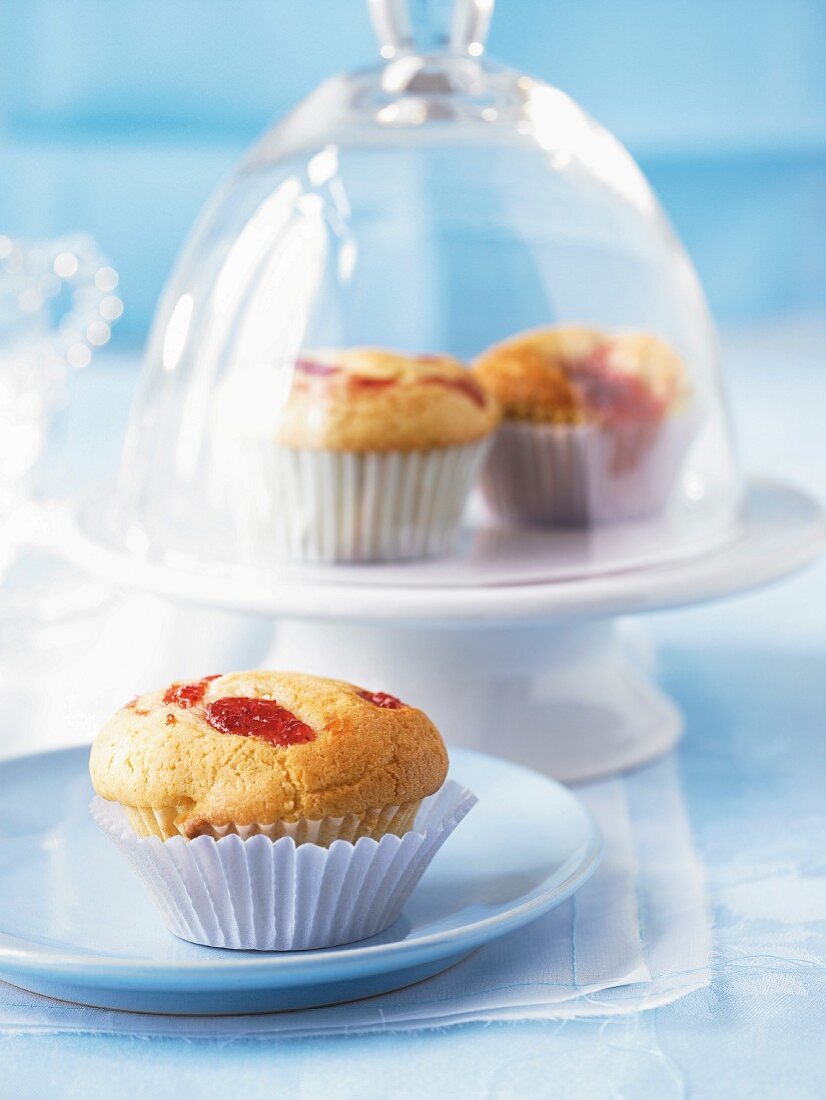 Jam muffins on a plate and under a glass cloche