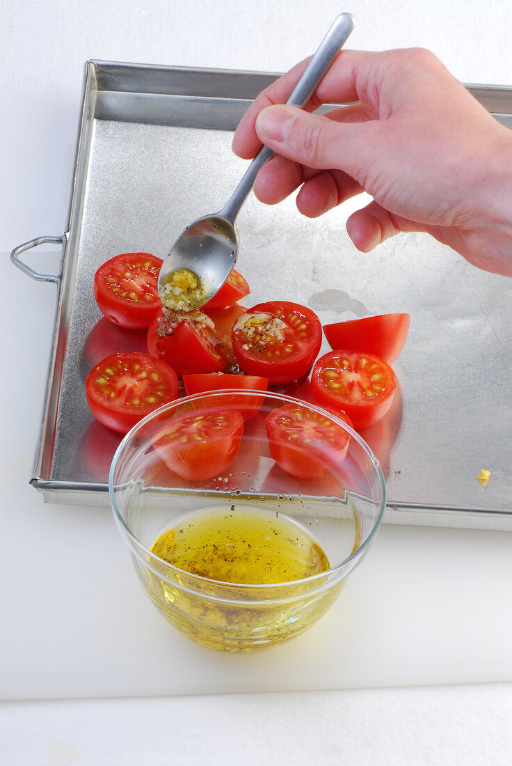Close-up of tomatoes being marinated in baking dish, step 1