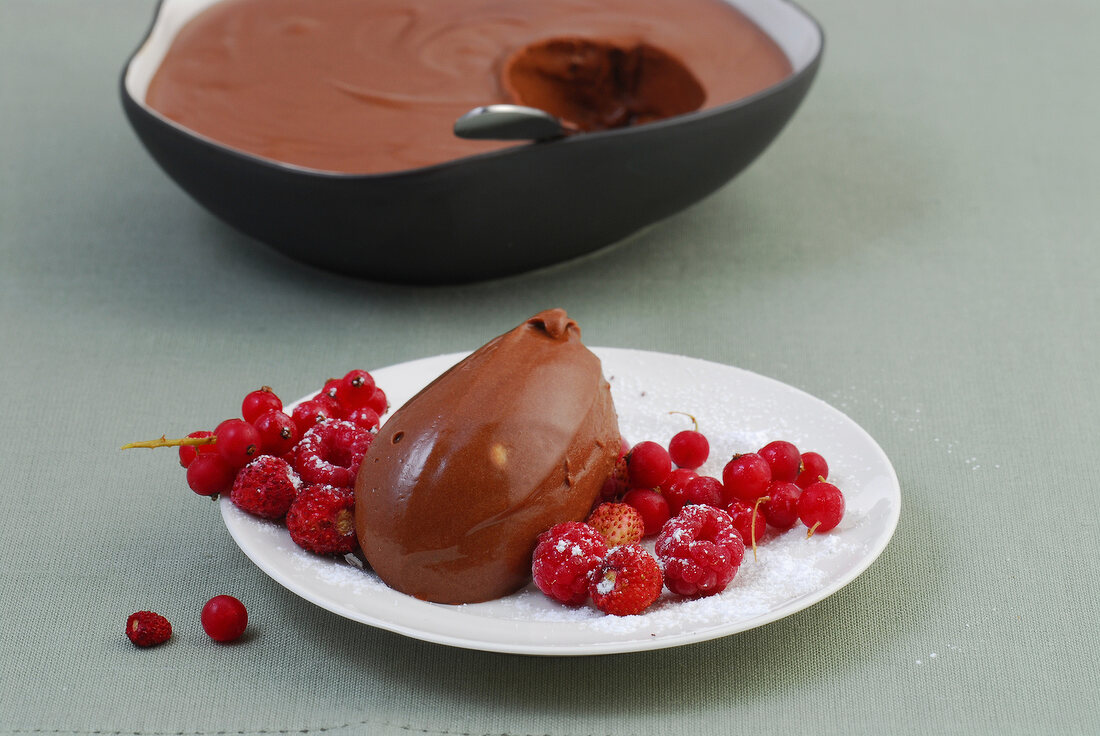 Scoop of chocolate mousse with red berries on plate
