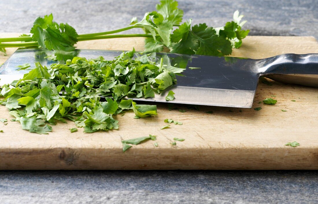 Coriander being chopped on a wooden board