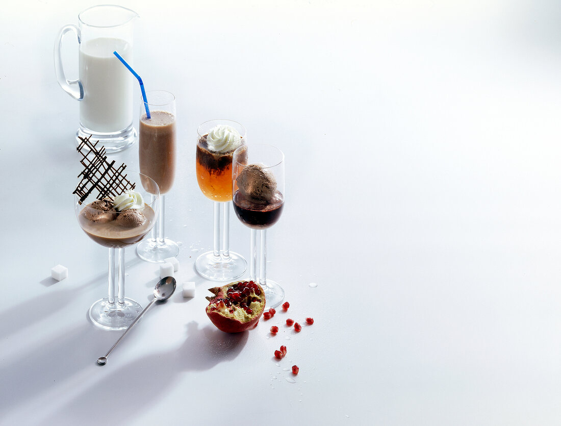 Variety of chocolate drinks with pomegranate on white background