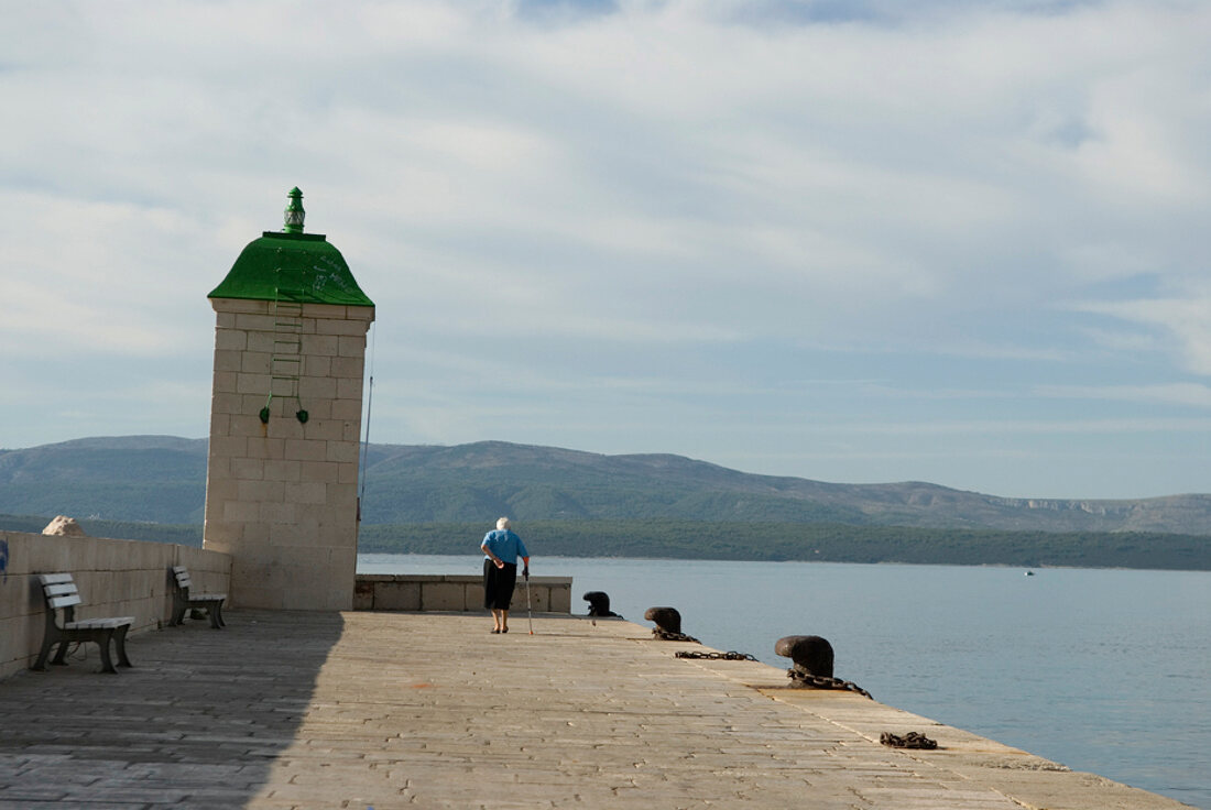 Pier in Brac, Bick aufs Meer und Gebirge, Wolken am Himmel.