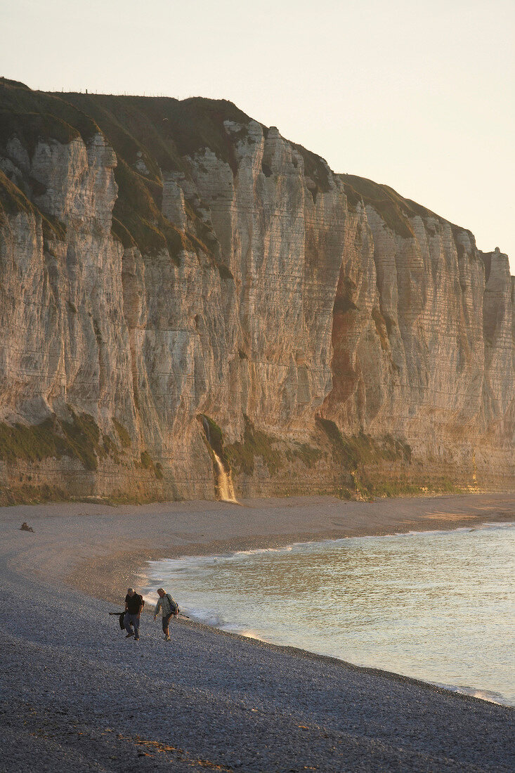 View of people walking on beach, cliffs at Cote d'Albatre in background, France