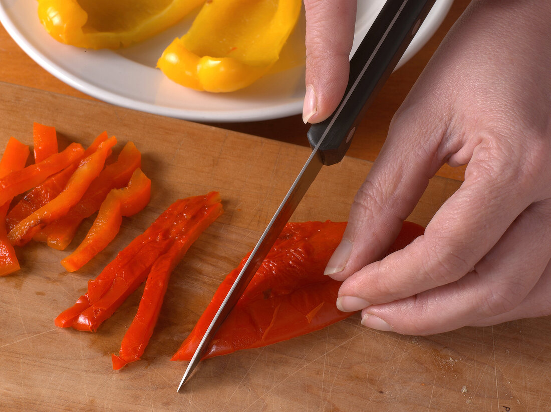 Peppers being cut into strips with knife, step 3