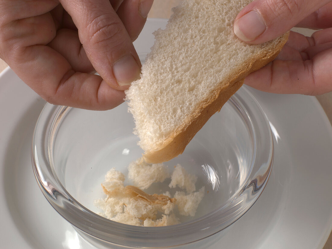 Slice of bread being broken into small pieces for preparation of orange aioli, step 2