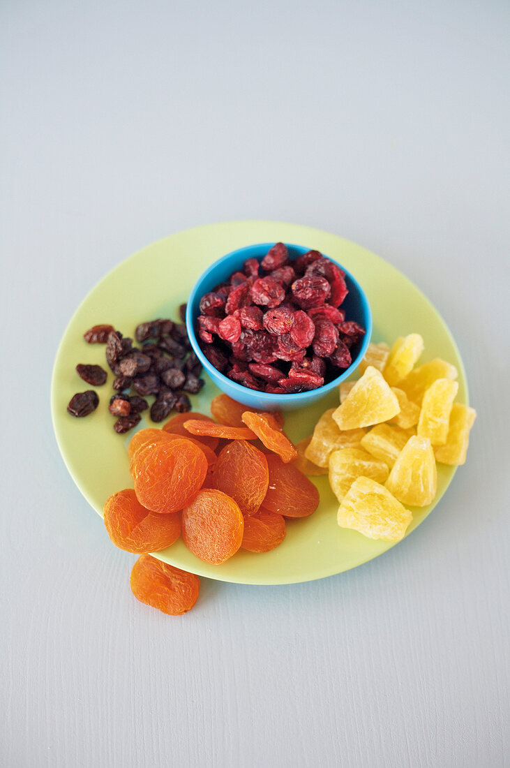 Blue bowl of raisins, apricot and pineapple on plate
