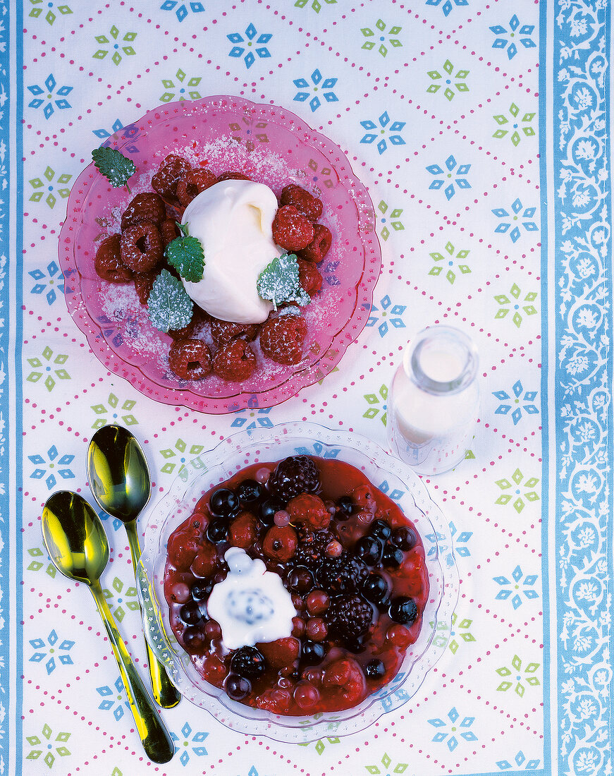 Red berry compote with custard and raspberries with eggnog cream in bowls