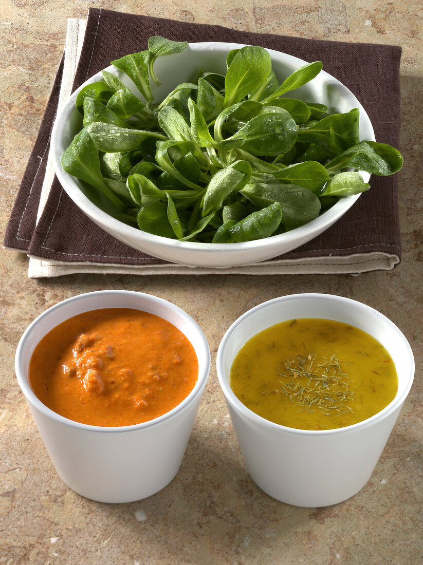 Corn salad leaves in bowl with dip and dressing in small cups