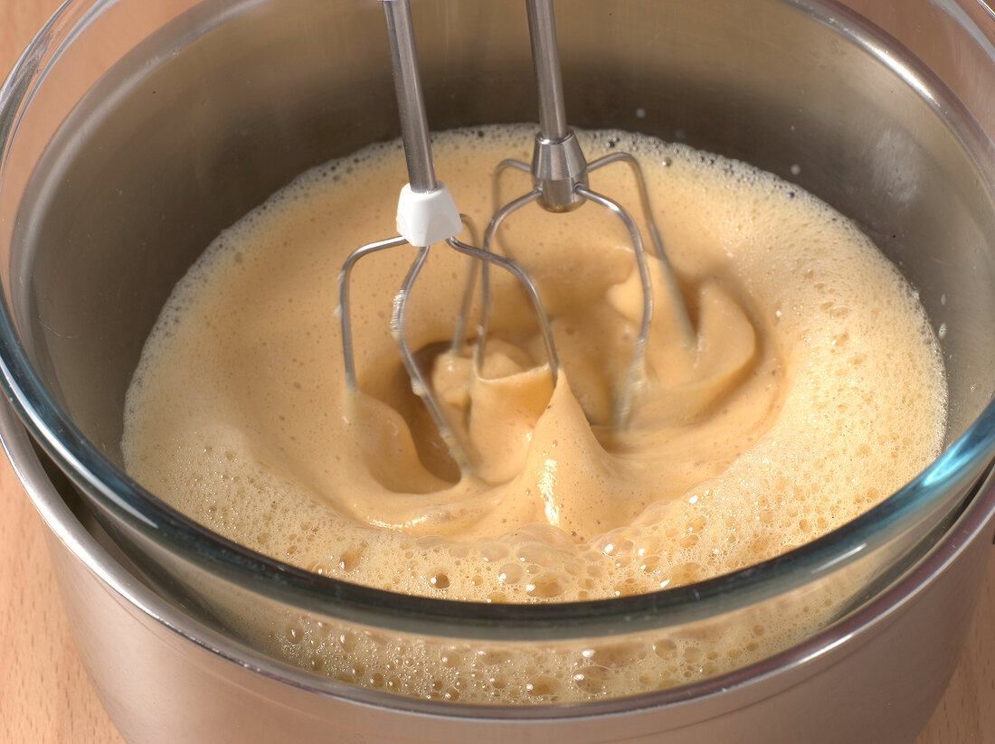 Mixture being beaten with hand mixer till frothy for preparation of sabayon sauce, step 3