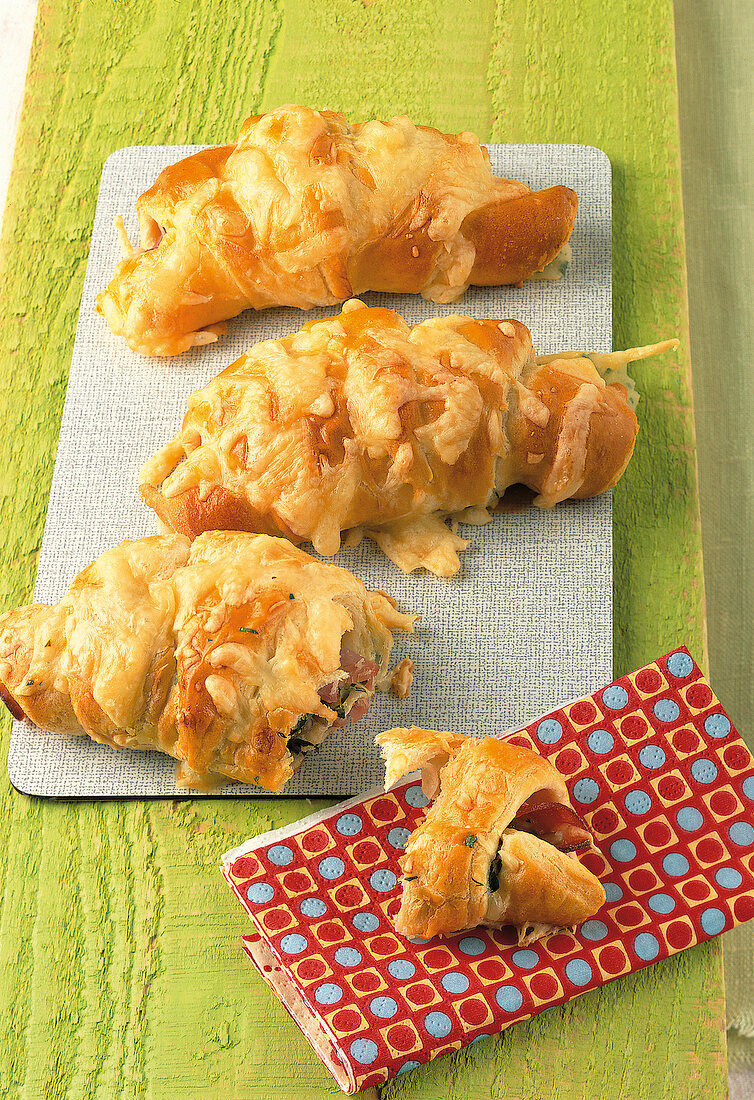 Backen, 3 Schinken-Käse- Croissants auf einem Brotbrett