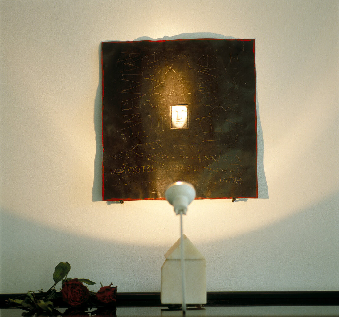 White wall with photo frame illuminated by lamp