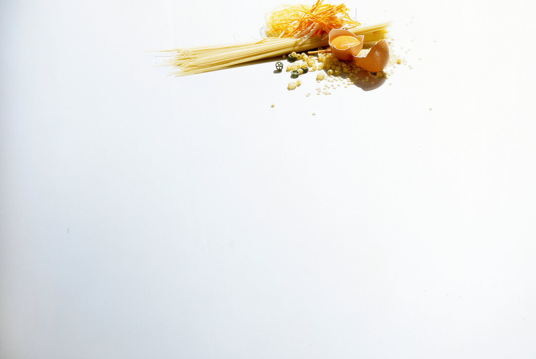 Raw pasta, egg, spaghetti, rice noodles and spaetzle on white background