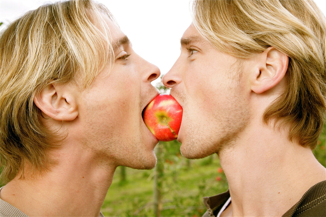 Blonde men biting into apple