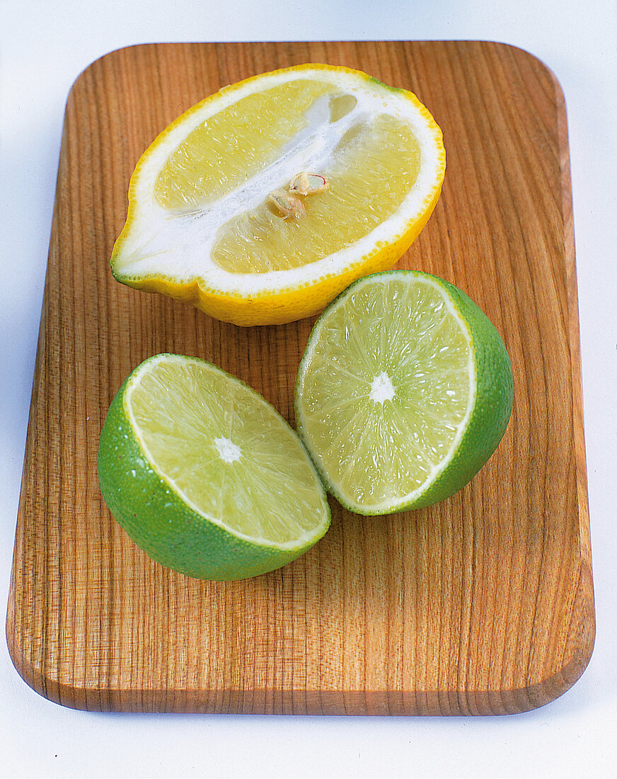 Kochen, Freisteller: halbe Zitrone, halbierte Limette auf Brett