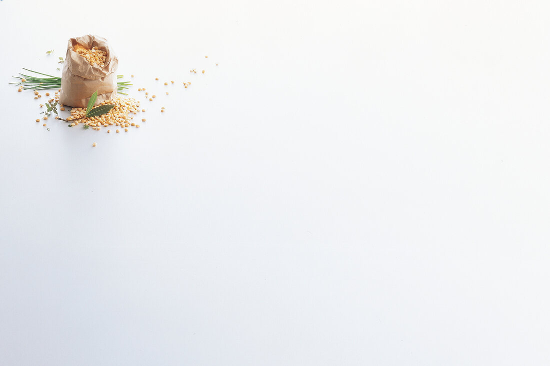 Yellow peas spilled out of paper bag and chives on white background