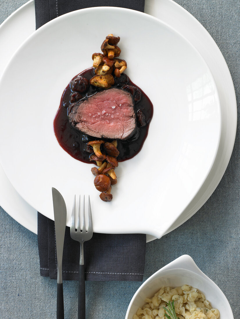 Fillet of sauerbraten with dried cherries and rosemary spaetzle on white plate