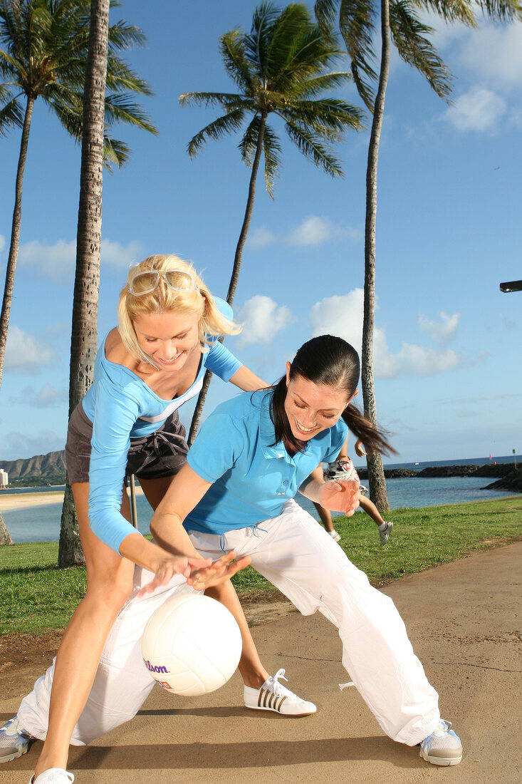 Zwei Frauen beim Ballspielen unter Palmen im Park