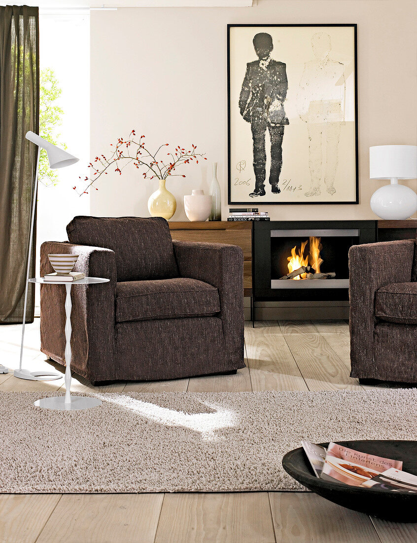 Room with armchair against fireplace and large painting on wall