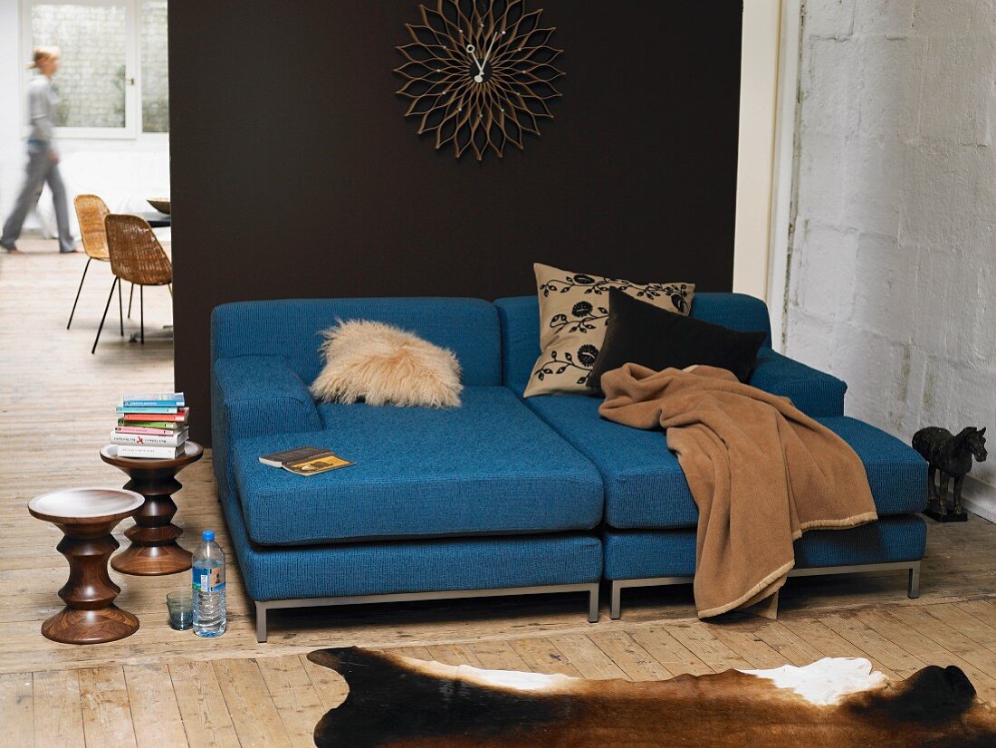 Blue sofa with scatter cushions and blanket against dark brown wall