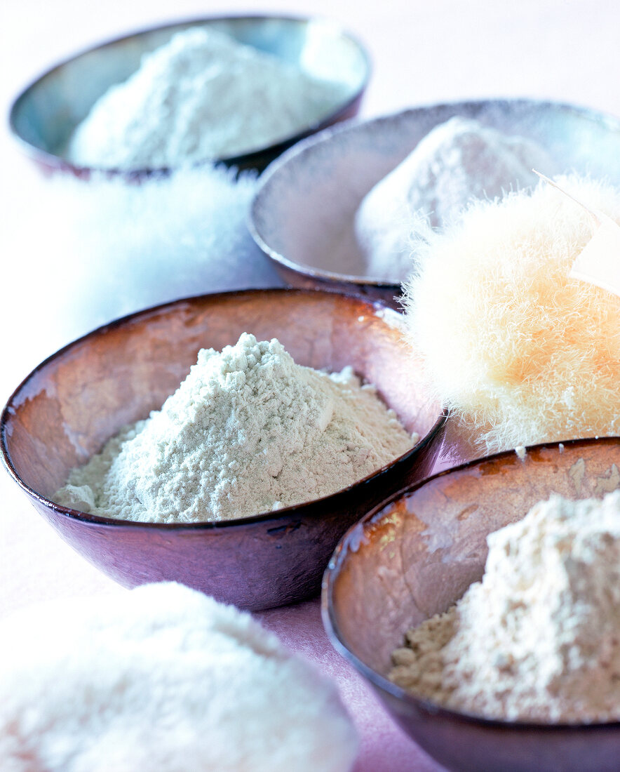 Close-up of various bowls with powder and powder brush