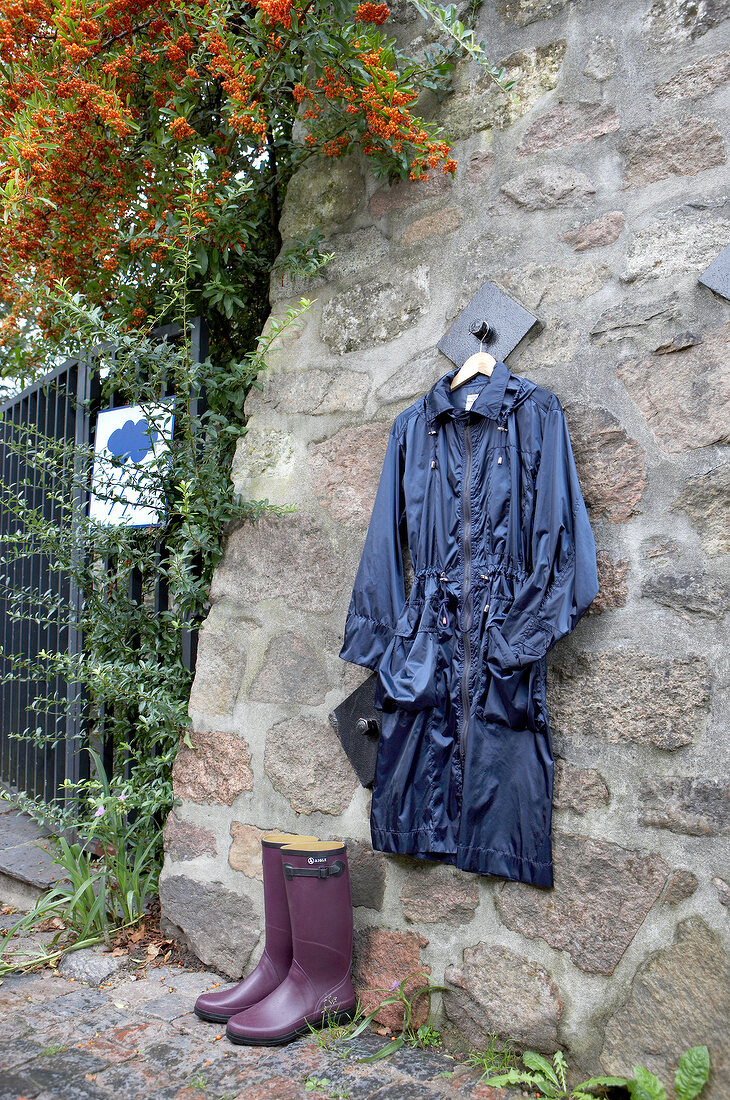 Blue nylon parka hanging on wall and rubber boots on side