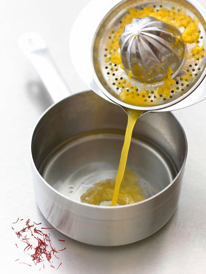 Close-up of juice being poured in pan from citrus squeezer